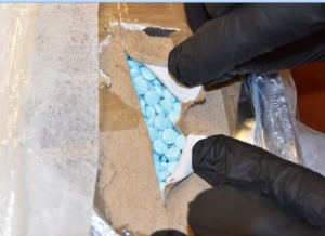 a package of drugs is opened to show blue pills inside 