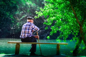 Elderly man sitting next to a river Elderly man sitting next to a river