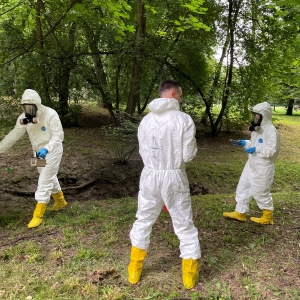 Justice Department personnel don hazmat suits and search with Ukrainian prosecutors and investigators through woods to detect environmental harm