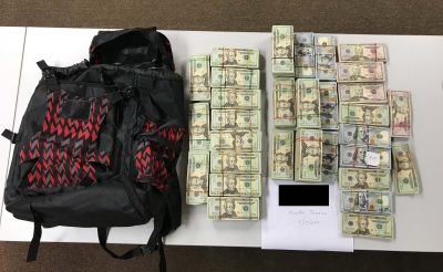 Black and red backpack with piles of money