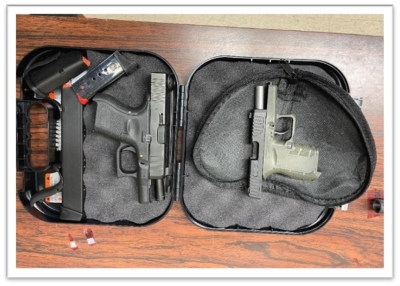 Two black guns and magazine in a gun case