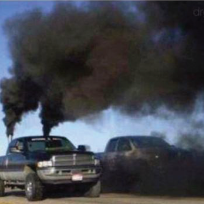 A truck "rolling coal" spews black clouds of exhaust into the air.