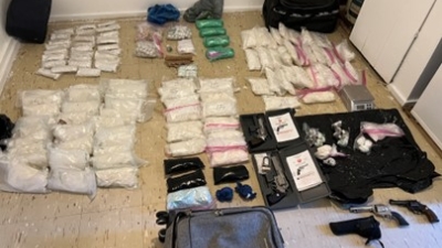 picture shows a large amount of seized drugs and guns 