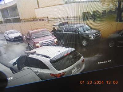 Photograph showing multiple cars parked and individual moving something from a red F-150 pickup truck to a black Chevrolet Tahoe.