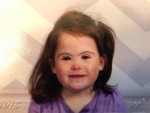 Maggie Miller in 2015 at a young age wearing a purple shirt with her hair in a half up side ponytail.