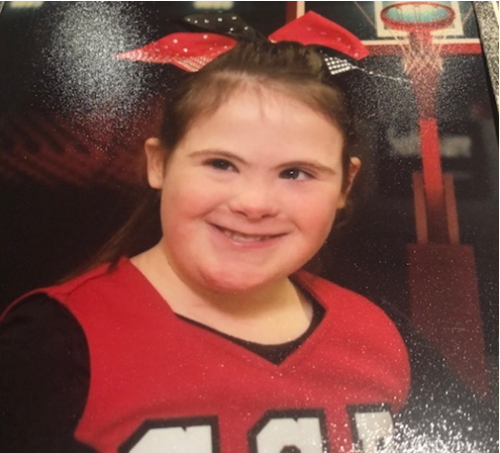 Maggie in her cheerleading uniform with a and black bow holding her hair in a ponytail