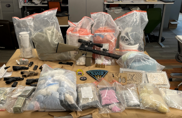 Multiple firearms, plastic bags containing narcotics (pills and powder) and cash displayed on table that was seized during search warrants