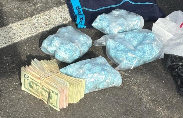 plastic bag containing blue pills and a stack of cash
