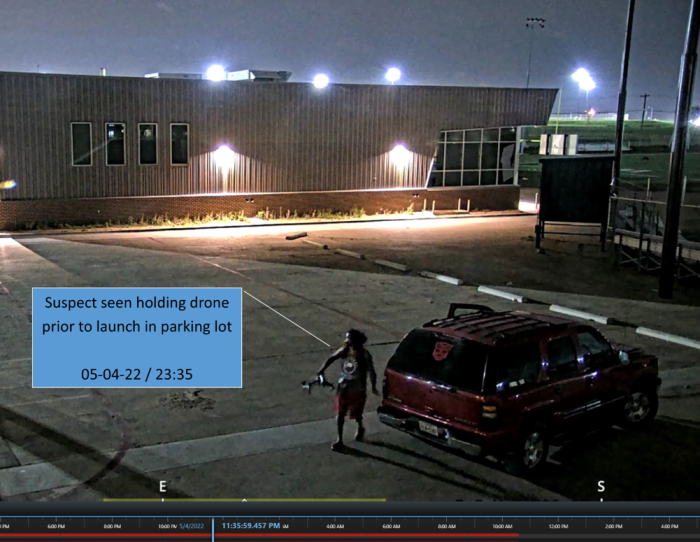 A man allegedy launches a drone next to a red Chevy Tahoe