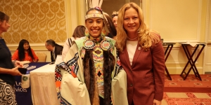 U.S. Attorney Trina A. Higgins with a Tribal Speaker/Dancer during a cultural presentation in a ballroom 