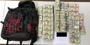 Black and red backpack with piles of money