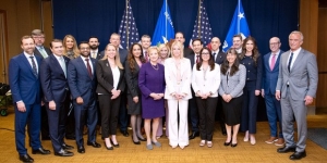 A group of 22 people standing in front of flags 