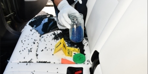 A person wearing white gloves holding a class container.