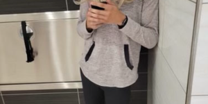 Image of person in blonde wig in bathroom stall wearing face mask