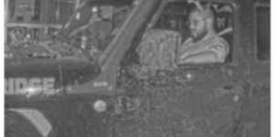 Black and white image depicting man driving.