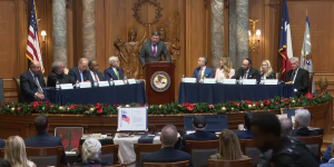 Associate Attorney General Stanley Woodward speaks at a podium joined on stage by members of the Religious Liberty Commission. 