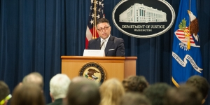 Makan Delrahim speaking at a podium in front of an audience of event attendees.