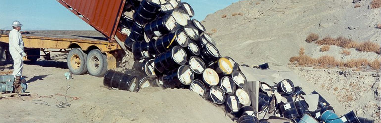 In the past, random stacking was the best available disposal method. Here drums are being dumped into a hole in a Pit in 1969. Courtesy of U.S. Senate.