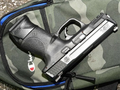 Black gun on top of camouflage backpack