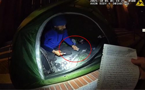 Photo of the defendant holding destructive devices in his tent.