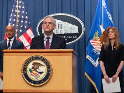 Merrick B. Garland speaks at the podium. To the left is U.S. Attorney for the southern district of New York Damian Williams, and to the right is DEA Administrator Anne Milgram. An American flag, the Department of Justice seal, and the Department of Justice flag are seen in the background.