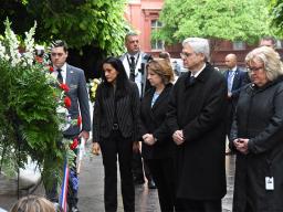 ASG Gupta, DAG Monaco, and AG Garland respectfully consider a wreath decorated with red, white, and blue flowers.