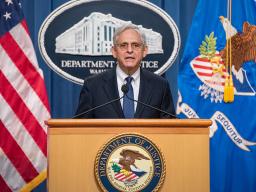 Attorney General Merrick B. Garland speaks at a podium bearing the Department of Justice seal.