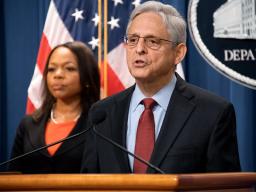 Attorney General Merrick B. Garland speaks at the Department of Justice podium. Behind him stands Assistant Attorney General Kristen Clarke and the American Flag.