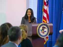 Associate Attorney General Vanita Gupta addresses the crowd from a podium bearing an Office of Justice Programs seal. The American flag and the Department of Justice flag are seen in the background.