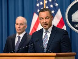 U.S. Attorney Breon Peace for the District of New York speaks at a podium with the Department of Justice seal in the background. To his left is Assistant Attorney General Matthew G. Olsen