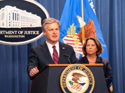 FBI Director Christopher Wray delivers remarks at a podium bearing the Department of Justice seal.