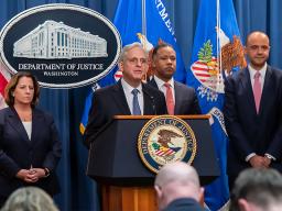 Attorney General Merrick B. Garland delivers remarks from a podium bearing the Department of Justice seal