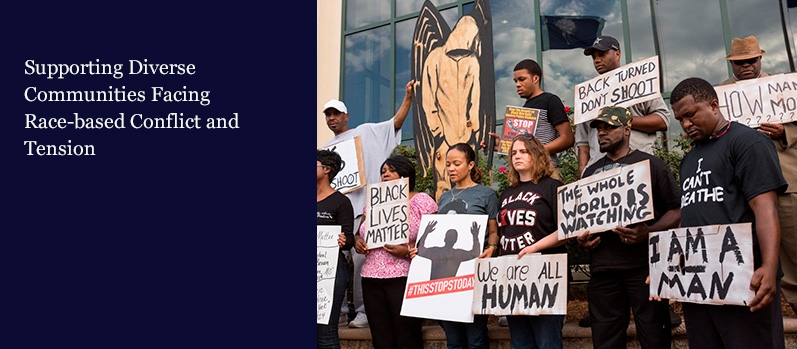A group of African American men and women stand with signs during a protest again a police shooting.